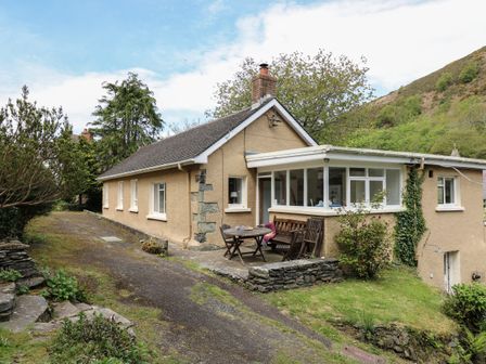 A single-story house with a patio table and chairs outside at Yr Odyn in Llangrannog Ceredigion