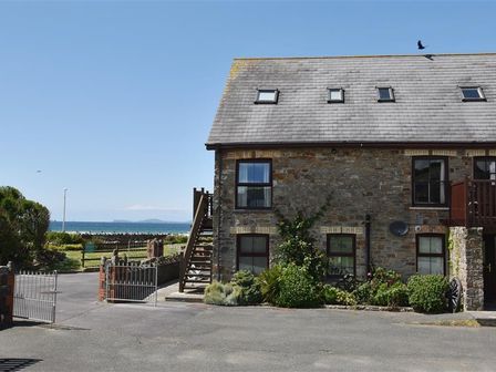 A stone house with windows and a roof with skylights near a gated driveway and ocean view at 5 The Coach House in Broad haven Pembrokeshire