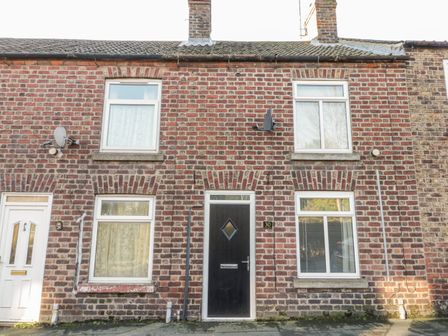 Exterior view of a two storey brick house with two chimneys and white framed windows at Scarborough Cottage in Driffield