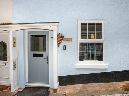 A light blue cottage door with a window and a house number 7 next to a window with white frame at Hillcroft Cottage Shaldon near Teignmouth