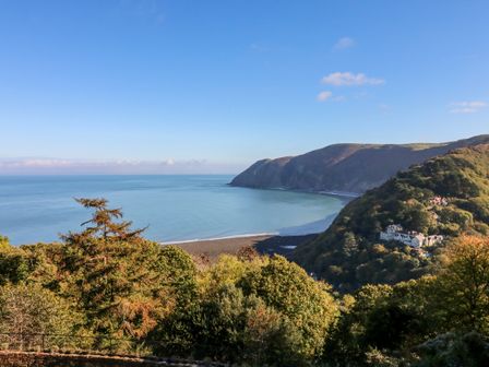 A coastal landscape with a bay surrounded by hills and trees at Blue Bay in Lynton