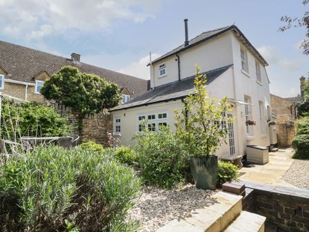 A white two-story house with a garden and outdoor seating area at Blundell's Cottage in Broadway