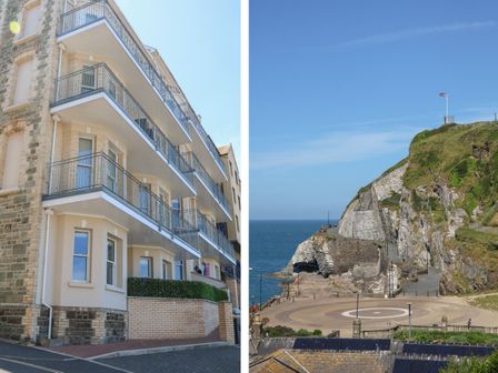 An apartment building with balconies and a coastal cliff with a flag at 1 Arlington Villas in Ilfracombe