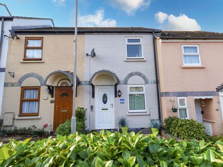 Front view of three terraced houses with plants and bushes in front at Kingfisher Cottage in Weymouth