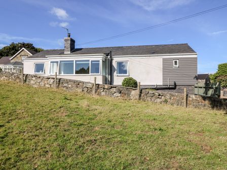 A single story house with stone wall and grassy yard at Berth in Afonwen near Criccieth