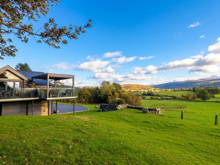A house with a deck overlooking a green landscape at Tyn Llwyn in Pencoed near Corwen