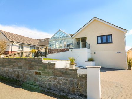 An exterior view of a house with a paved driveway and a conservatory at Auverne Poundstock near Widemouth Bay