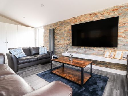 A living room with leather sofas a wooden coffee table and a large wall mounted television at Box Tree Escapes Wennington near Kirkby Lonsdale