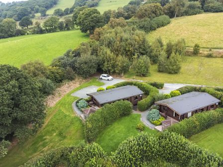 Two single story houses surrounded by hedges and greenery in a rural area at Valley View in Rhayader