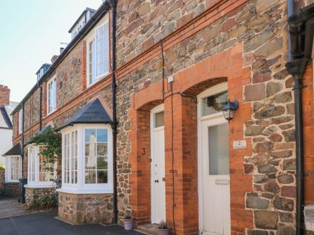 Stone and brick terraced houses with white framed windows and doors on a street at 3 Lowerbourne Terrace in Porlock