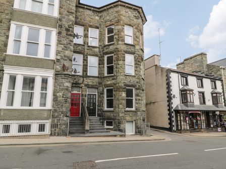 A street view of stone and brick buildings with shops and residential entrances in Barmouth