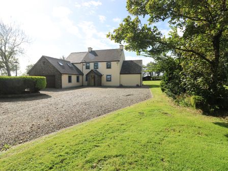 A detached house with a gravel driveway surrounded by grass and trees at Mountain Farm in Broad Haven