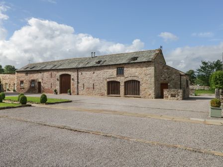 Stone barn building with gravel driveway and small hedges at Byre Cottage Great Asby near Appleby-In-Westmorland