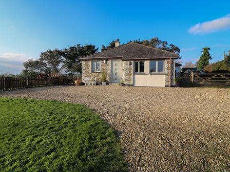 A small stone house with a gravel driveway and grass lawn at Valley View in Mevagissey