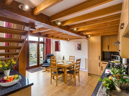 A kitchen and dining area with wooden beams and a dining table set for four at Nest Barn in Keswick