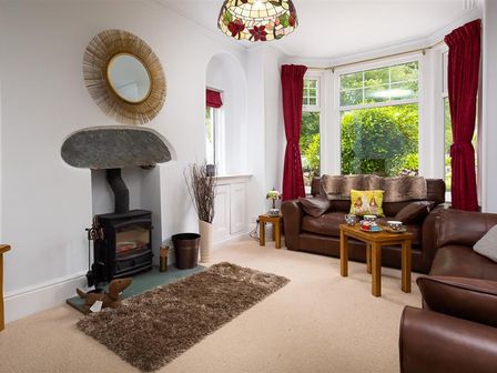 A living room with brown leather sofas a wood stove and red curtains at Ellerthwaite House in Windermere