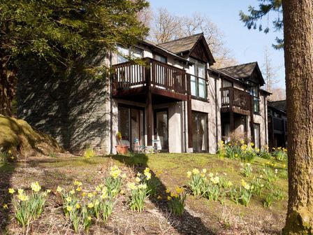 A building with balconies and glass doors surrounded by flowers and trees at Ramblers Rest in Ambleside