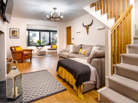 A living room with a gray sofa and patterned rug near stairs at Foxrock in Bowness