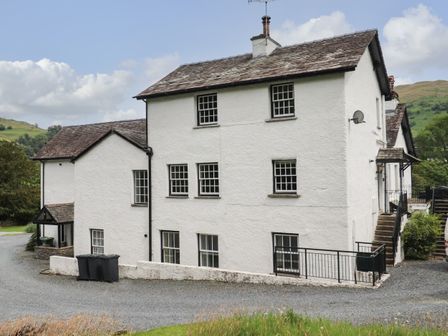 A white two-story house with multiple windows and a gravel driveway at Millerbeck in Ambleside