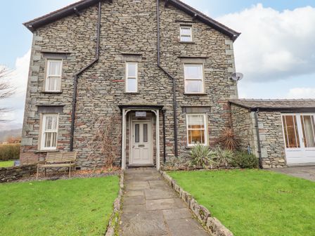 A stone house with a central door and windows on either side and a path leading to the door at Honeywood House in Grasmere