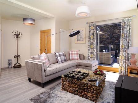 A living room with a sectional sofa and glass coffee table with tic tac toe game at Old Wool Loft Ambleside