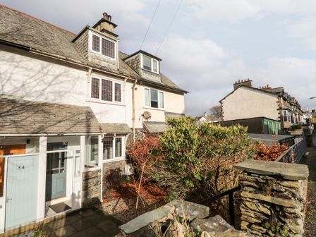 A row of stone and stucco houses with small porches and shrubs in front at Lakestone Cottage in Windermere