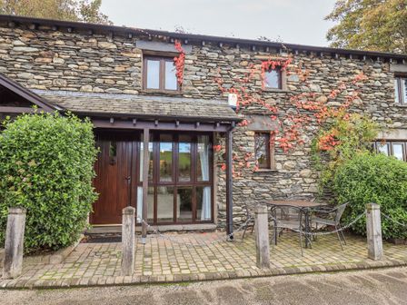 Stone cottage exterior with wooden door two windows outdoor table and chairs on paved area at Gowan Cottage in Ings