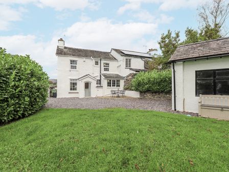A house with a garden and patio furniture at Smithy Cottage at Bowland Bridge, Bowness