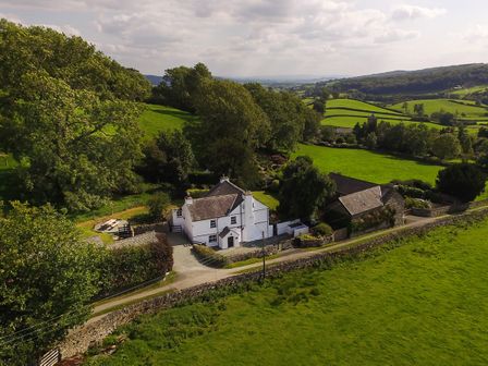 A white house with surrounding trees and green fields at Low Cartmell Fold in Crosthwaite