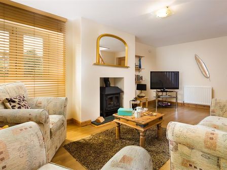 A living room with patterned armchairs wooden blinds a wooden coffee table and a television at Agathi in Keswick