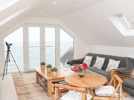 A living room with a telescope by the window and wooden furniture at St Julien in Dawlish