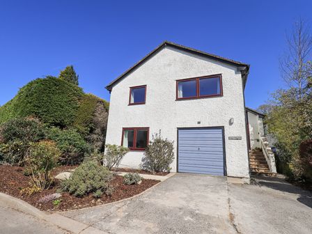 A two-story white house with a garage and garden in front at Striding Home in Ambleside