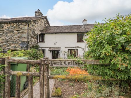 A stone and white cottage with a wooden gate and garden in front at Park Cottage in Ambleside