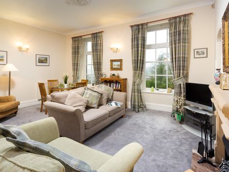 A living room with sofas dining table television and fireplace at High Borrans in Ambleside