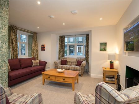 A living room with sofas curtains a wooden coffee table and a television at Heatherley in Ambleside