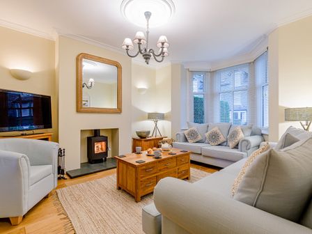 A living room with two sofas a wooden coffee table a television and a fireplace at Oak House in Keswick