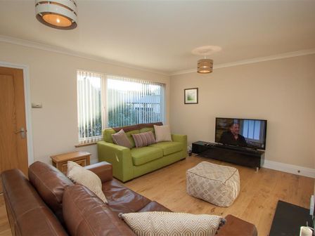 A living room with two sofas a television and an ottoman at Beckside in Ambleside