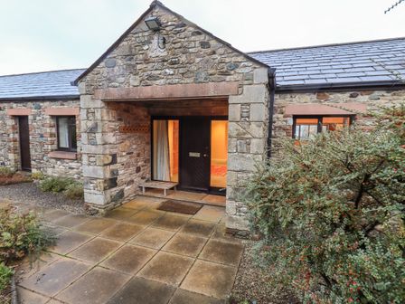Stone exterior of a house with a covered porch and paved walkway at Low House in Ullswater