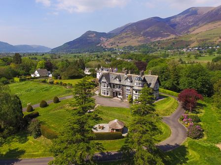A large house with a driveway and garden surrounded by trees and mountains at Bristowe Hill in Keswick