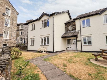 A white stone residential building with windows and a pathway in front at Fairview in Bowness
