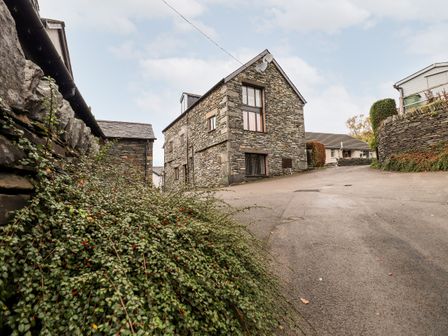 A narrow street with stone buildings and walls with bushes along the side at Squirrel Bank in Ambleside