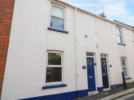 The exterior of a white terraced house with blue doors and window sills at South Harbour Cottage in Weymouth