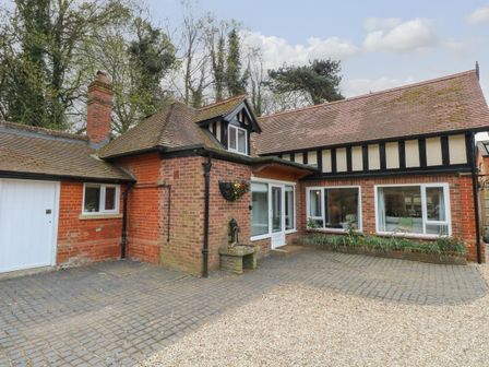 Exterior of a brick and timber house with cobblestone and gravel driveway at The Lodge in Wroxham