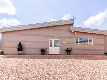A single story building with beige horizontal siding double doors and plants outside at The Croft in Leigh Sinton
