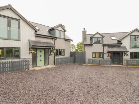 Two modern houses with fenced yards and gravel driveway at Big Azzles in Tyn-y-Gongl near Benllech