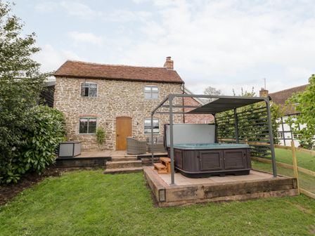 A stone house with a patio hot tub and outdoor seating at Old Farm Cottage in Eastham near Tenbury Wells