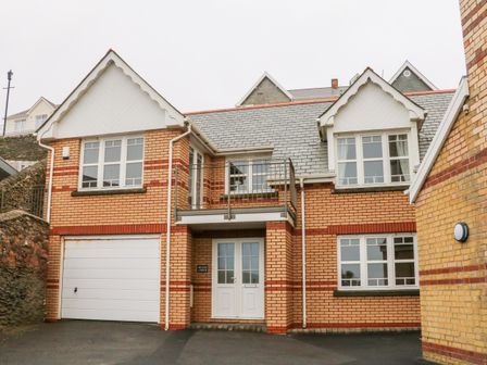 The front exterior of a two-story brick house with a garage and double front doors at Beach Lodge in Woolacombe