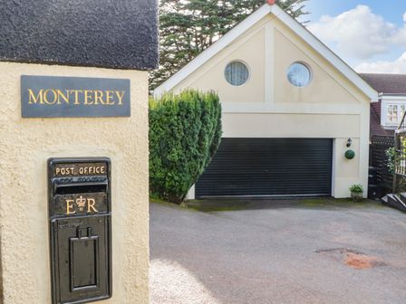 A driveway with a black garage door and two round windows above at Monterey in Torquay