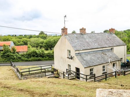 A two chimney house with a fenced yard and a sloped grass area at Sarah Magees in Garrison County Fermanagh