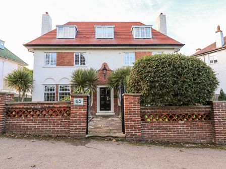 A two story house with white walls and a red roof behind a low brick wall with a gate at Yardley Manor in Scarborough